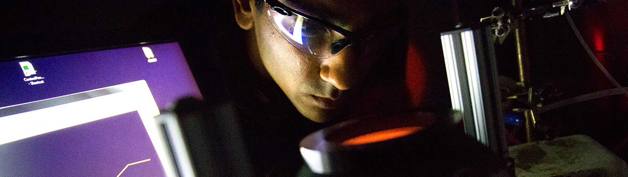 a close up image of the researcher umar aslam looking into the light sourse used during the experiments that revealed how the silver nanocubes captured energy and delivered it to the platinum shells