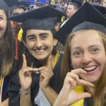 Students at commencement spell "ChE" with hands