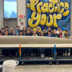 Michigan Concrete Canoe team pictured behind canoe in workshop.