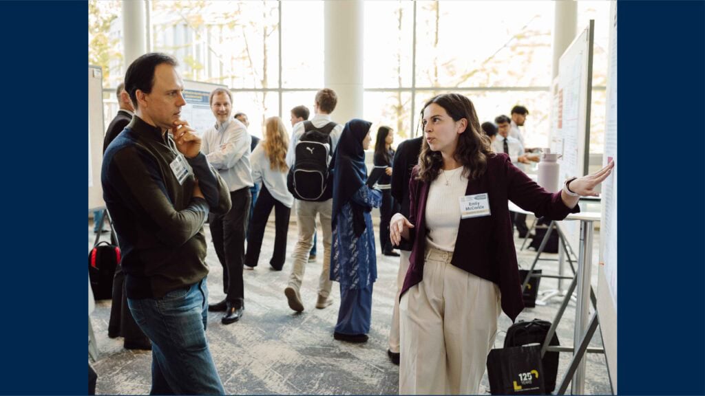 Graduate students engage in discussions with peers and faculty during the poster session.